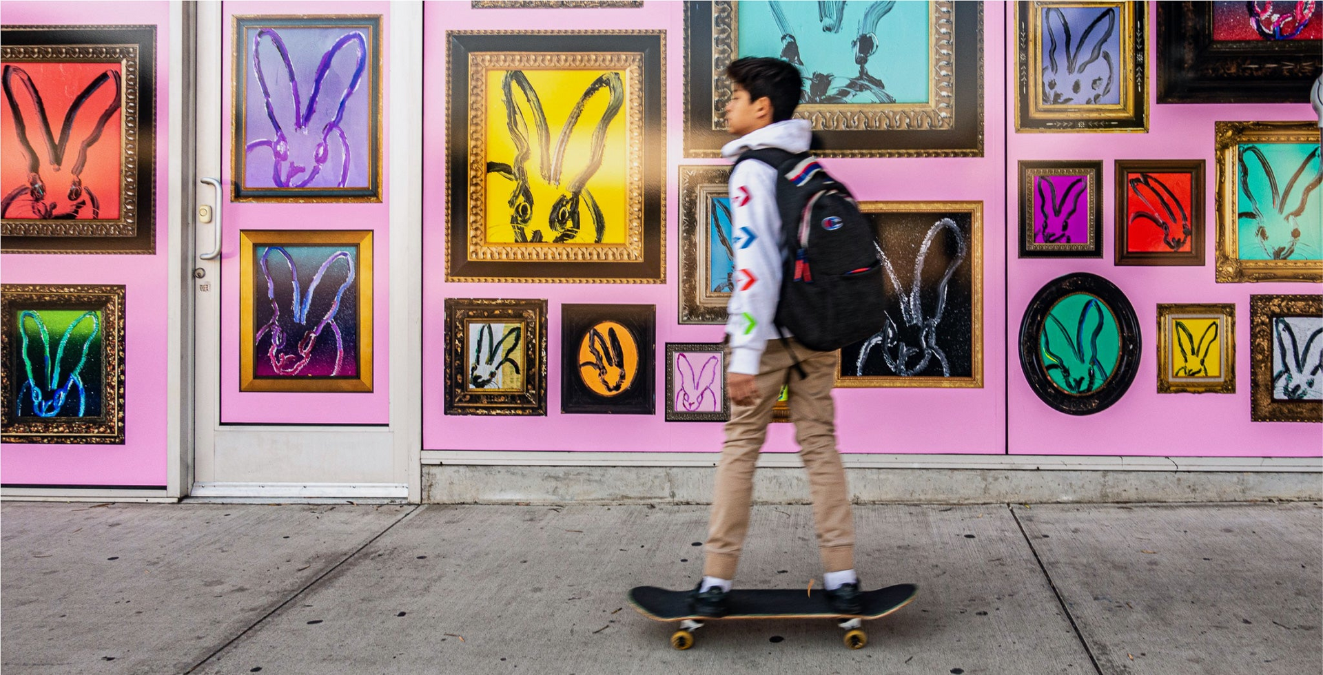 Kid Skateboarding in front of wallpaper mural of Hunt Slonem Paintings